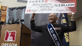 Cheng Saephan hält auf einer Pressekonferenz in der Lotteriezentrale von Oregon in Salem einen übergroßen Scheck in die Höhe. Foto: Jenny Kane/AP/dpa